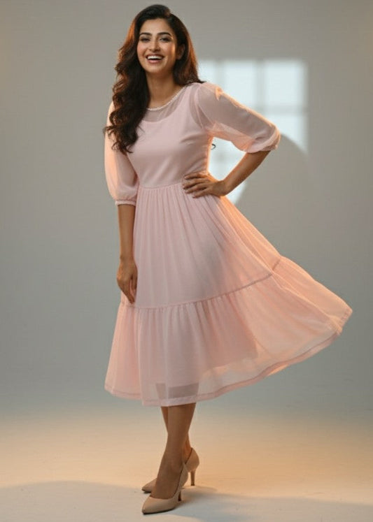 Woman wearing a light pink dress posing against a neutral background